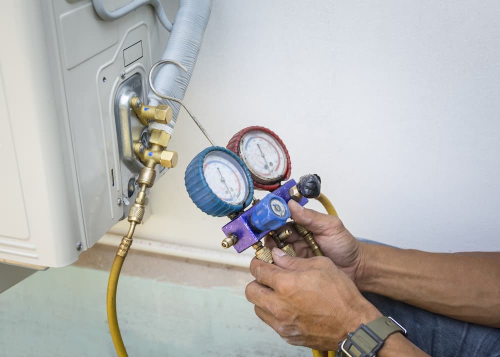 Man inspecting air conditioner with pressure gauge for indoor air quality